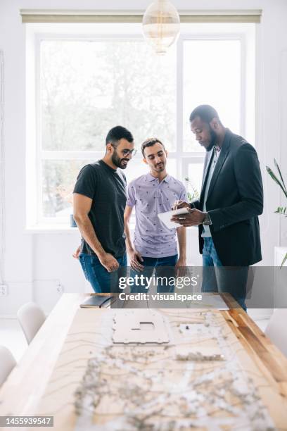 l’agent immobilier explique les options de financement disponibles pour le nouveau développement, tandis que le couple gay écoute attentivement - real people lifestyle photos et images de collection