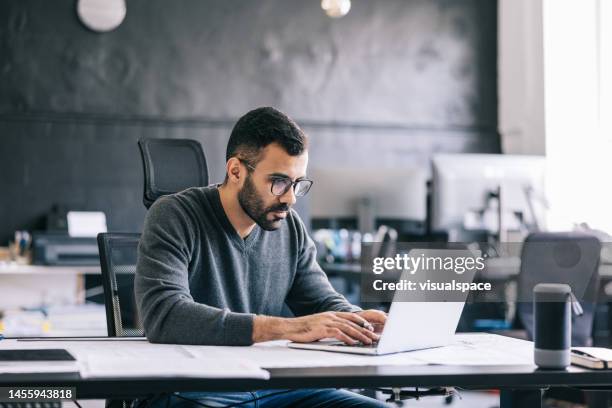 the architect takes notes on the blueprint, then inputs them into the laptop to keep an digital record of the design process. - businessman working stock pictures, royalty-free photos & images