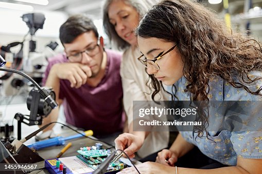 College instructor assisting electrical engineering students College instructor assisting electrical engineering students
