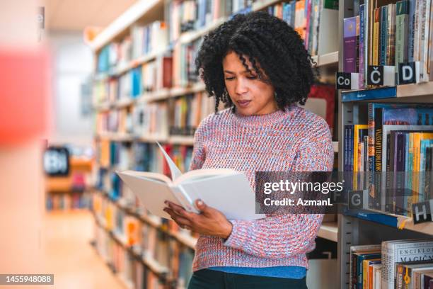 hispanische frau in den 30ern blättert durch ein buch - librarian stock-fotos und bilder