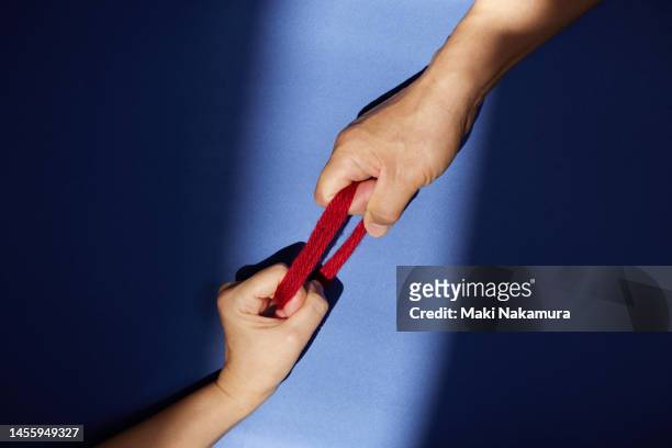 the hand holding the bundle of red thread is illuminated by a spotlight. - 調布 stockfoto's en -beelden