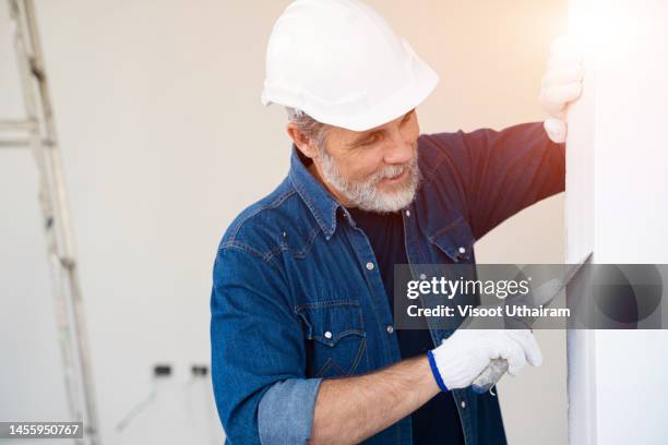 skilled worker is putting up the wall tiles,renovating the house concept. - maçon photos et images de collection