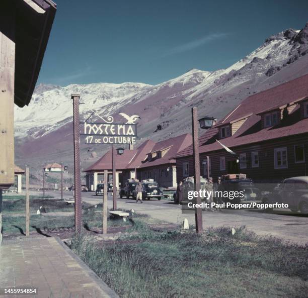 Pedestrians and visitors walk along a street past the Hosteria 17th October Inn at a settlement on the edge of the Andes mountain range in the...