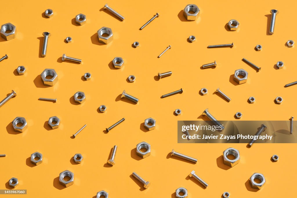 Many Hex Nuts And Screws On Yellow Background