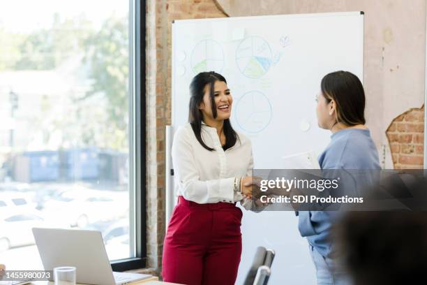 weiblicher ceo schüttelt weiblicher mitarbeiterin die hand - indianischer abstammung stock-fotos und bilder