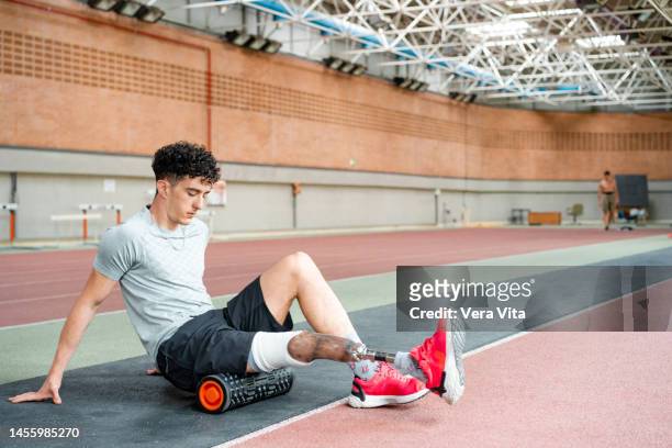 full length view of young man with prosthetic leg working out on sport stadium indoors. - piede artificiale per lo sport foto e immagini stock