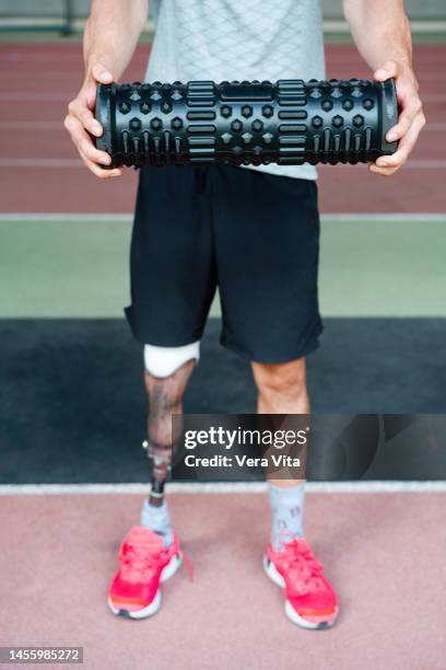 cropped detail of young man with prosthetic leg holding fitness equipment at stadium athletics track - vita shorts fotografías e imágenes de stock