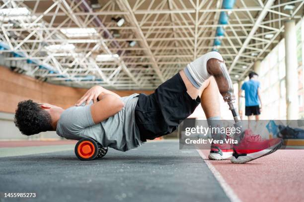 low angle view of young man with prosthetic leg working out on sport stadium indoors. - vita shorts fotografías e imágenes de stock