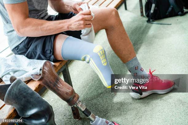 unrecognizable caucasian young man with leg stump changing professional prosthesis leg at gym indoors - vita shorts fotografías e imágenes de stock