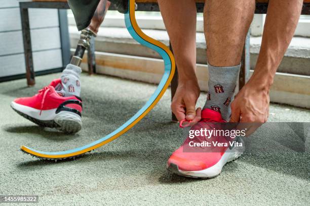 cropped detail of unrecognizable male runner with prosthesis leg tie sneakers shoelaces indoors - vita shorts fotografías e imágenes de stock