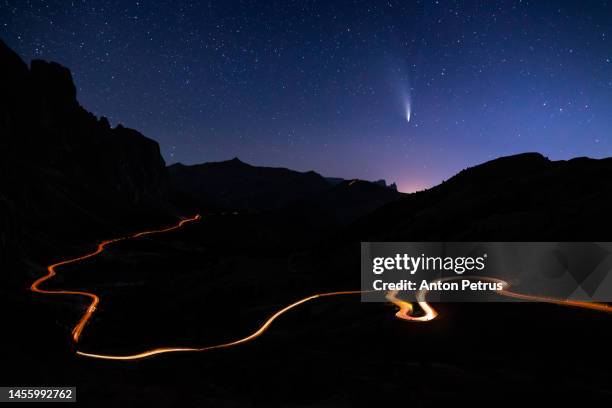 comet c/2022 e3 (ztf) over the road in the mountains at night - comite foto e immagini stock