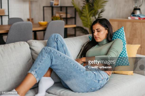 young woman having period cramps at home - pm stock pictures, royalty-free photos & images