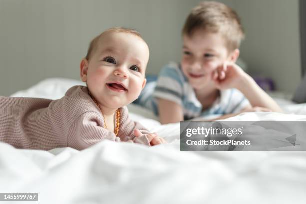 hermano y su hermanita en la cama de casa - baby girls fotografías e imágenes de stock