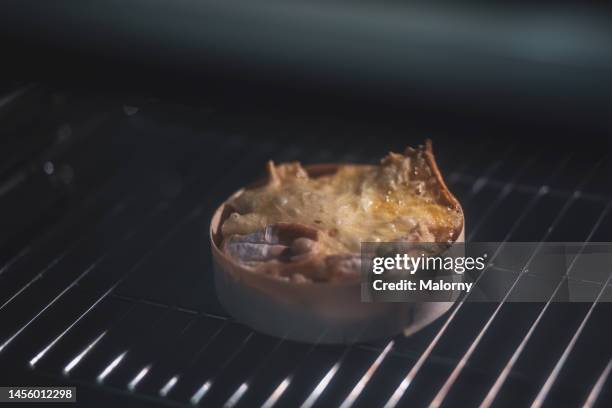 close-up of cheese baking in the oven. black background. - camembert stock-fotos und bilder