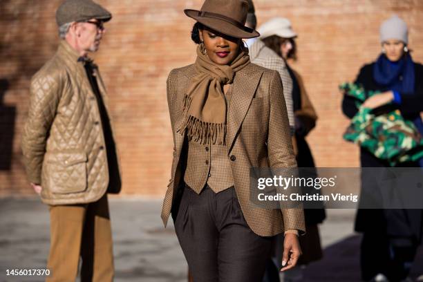 Angelique Noire wears brown hat, scarf, blazer, pants at Fortezza Da Basso on January 12, 2023 in Florence, Italy.