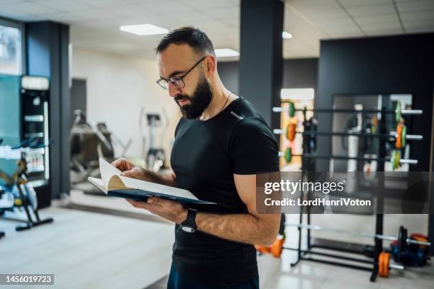 male fitness trainer reading schedule - sports venue employee stock pictures, royalty-free photos & images