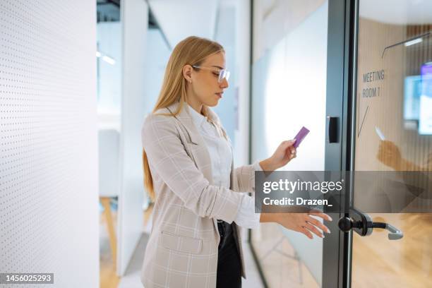 businesswoman in office opening the meeting room door with contactless card key - chave cartão imagens e fotografias de stock