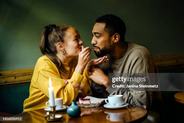 girlfriend feeding bite of dessert to her boyfriend at cafe - girlfriend fotos stockfoto's en -beelden