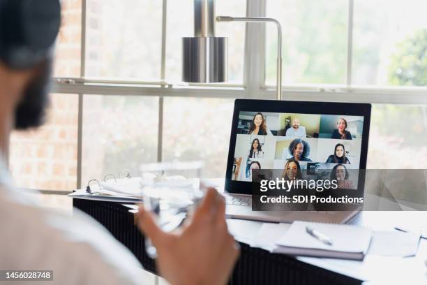 over-the-shoulder view unrecognizable man using laptop for virtual meeting - young businessman using a virtual screen stockfoto's en -beelden