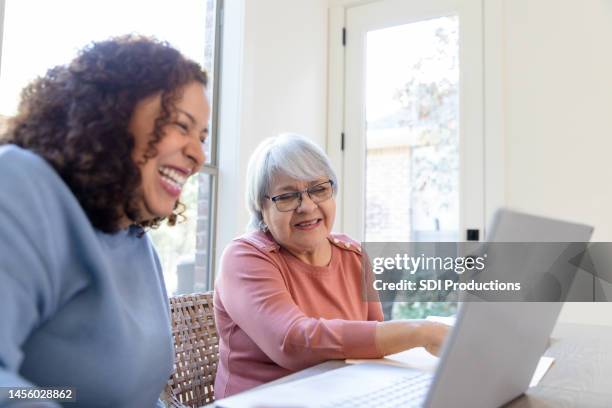 mother and daughter laugh at funny online videos - senior using computer stock pictures, royalty-free photos & images