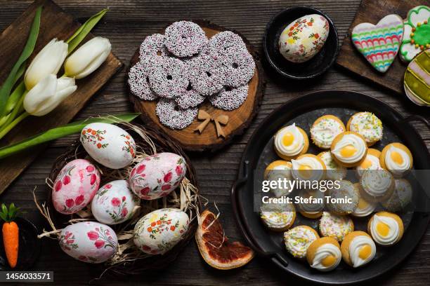festive easter table with easter eggs, sweet biscuits and decorations - easter breakfast stock pictures, royalty-free photos & images