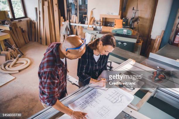 male and female carpenters  looking at blueprints - plaid shirt stock pictures, royalty-free photos & images