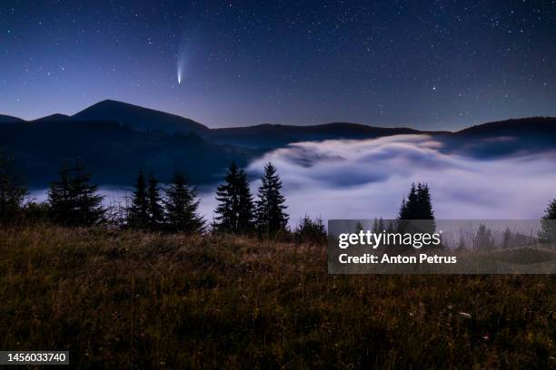 comet c/2022 e3 (ztf) at night over misty mountains - comet stock-fotos und bilder