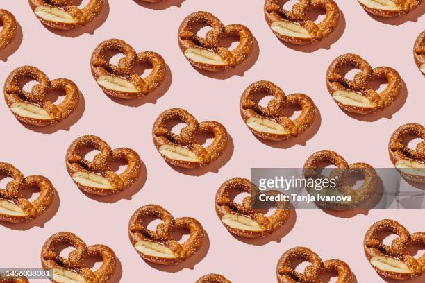creative layout with bread pretzels. pattern of bakery products handmade on pink background. modern minimal food photography collage in pop-art style. flat lay, top view - breze stock-fotos und bilder