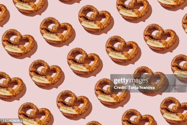 creative layout with bread pretzels. pattern of bakery products handmade on pink background. modern minimal food photography collage in pop-art style. flat lay, top view - pretzel stockfoto's en -beelden