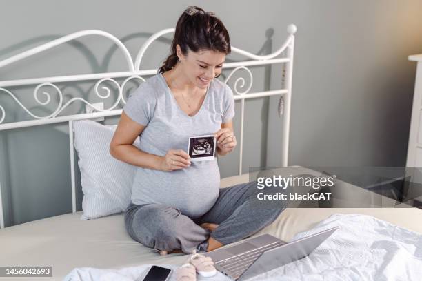 pregnant woman holding her baby sonography and talking on a video call - cat scan stockfoto's en -beelden