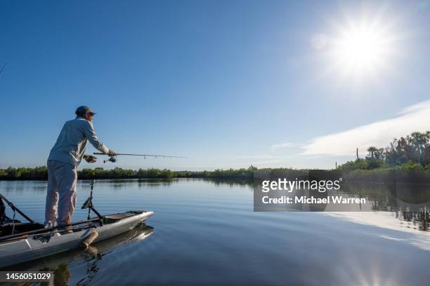 pesca de kayakista de pie en florida - kayak barco de remos fotografías e imágenes de stock