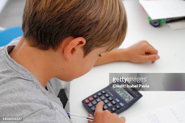 student uses calculator to help with math homework - child prodigy stockfoto's en -beelden