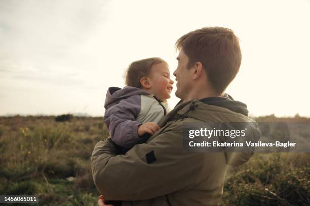 happy baby in dad's arms in the sunset light - face happy sun stockfoto's en -beelden