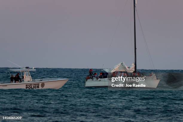 Customs and Border Protection, along with local law enforcement officials and other agencies, tend to a sailboat carrying more than two dozen Haitian...