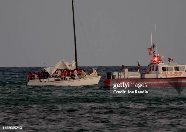 Customs and Border Protection, along with local law enforcement officials and other agencies, tend to a sailboat carrying more than two dozen Haitian...