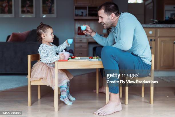 kleinkind mädchen und papa toast während der teeparty - familie eltern stock-fotos und bilder