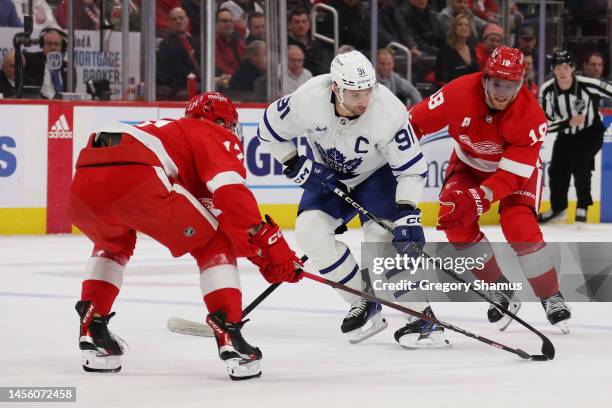 John Tavares of the Toronto Maple Leafs tries to split Filip Hronek and Andrew Copp of the Detroit Red Wings during the first period at Little...