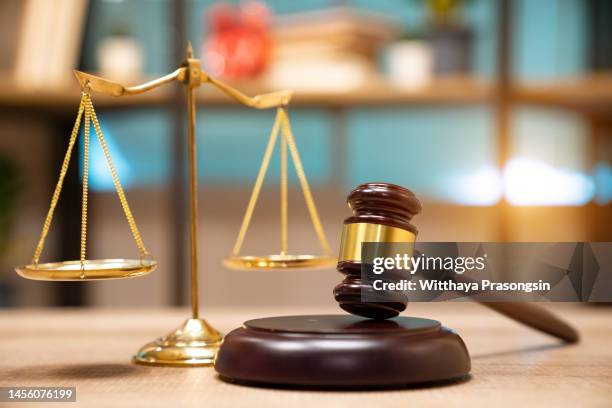 business and lawyers discussing contract papers with brass scale on desk in office. law, legal services, advice, justice and law concept picture with film grain effect - laws stockfoto's en -beelden