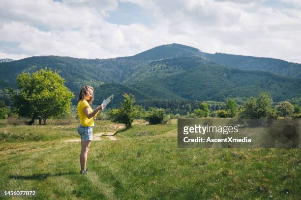 young woman uses map in meadow - escape rom stock pictures, royalty-free photos & images