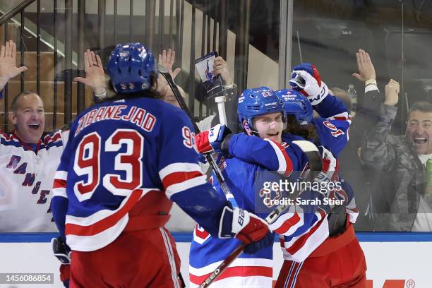 Mika Zibanejad and Artemi Panarin celebrate with Adam Fox of the New York Rangers after Fox's game-winning goal during overtime against the Dallas...