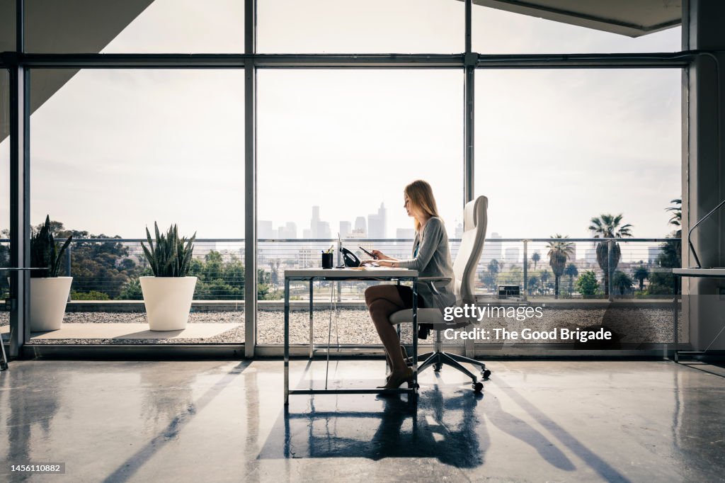 Side view of female entrepreneur sitting at desk working in office