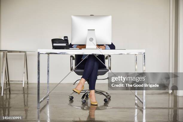 businesswoman sitting behind desktop pc in office - office front desk stock-fotos und bilder