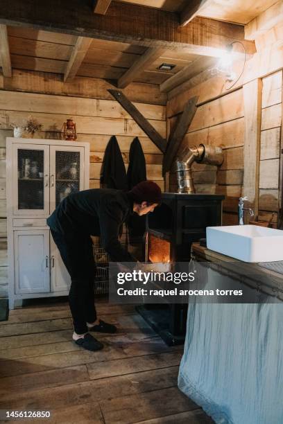 adult man lighting the fireplace - buening shack stock pictures, royalty-free photos & images