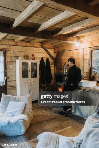 adult man warming himself by the fireplace - buening shack stock pictures, royalty-free photos & images