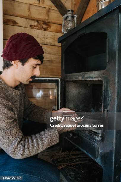 adult man lighting the fireplace with a match - buening shack stock pictures, royalty-free photos & images