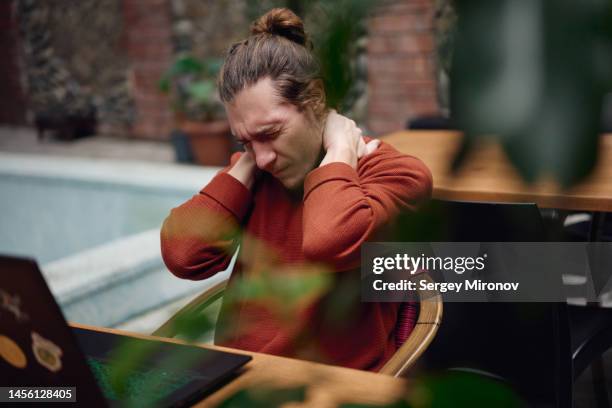 man freelancer massaging his neck after long working on laptop - neck pain stock-fotos und bilder