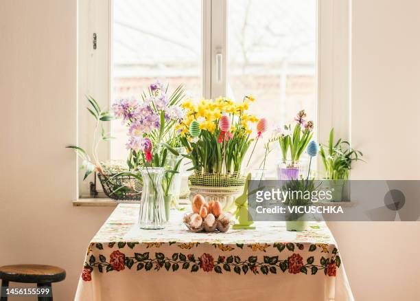 domestic easter still life with flowers, easter eggs and decoration on table at window background - easter flowers stock pictures, royalty-free photos & images
