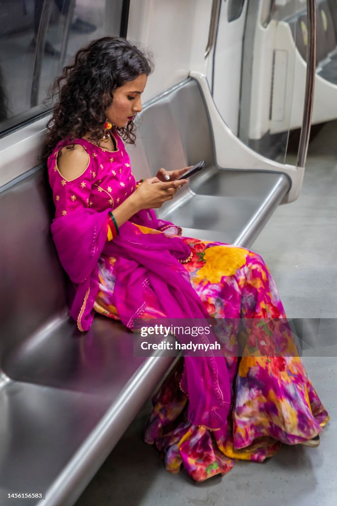Indian girl using a mobile phone in a subway train, India