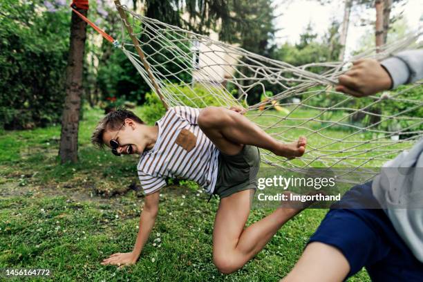 two teenage boys playing on a hammock on a spring day - boy lying down stock pictures, royalty-free photos & images