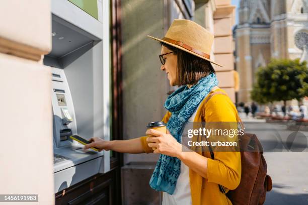 junge frau hebt bargeld vom geldautomaten ab - atm screen stock-fotos und bilder